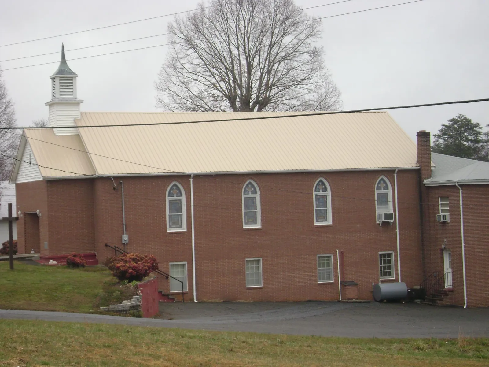 New tan metal roof on a brick church with a white steeple in Felton